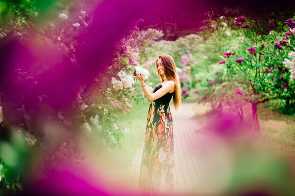 Young beautiful woman in summer blooming garden