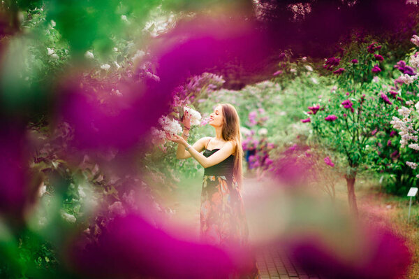 Young beautiful woman in summer blooming garden