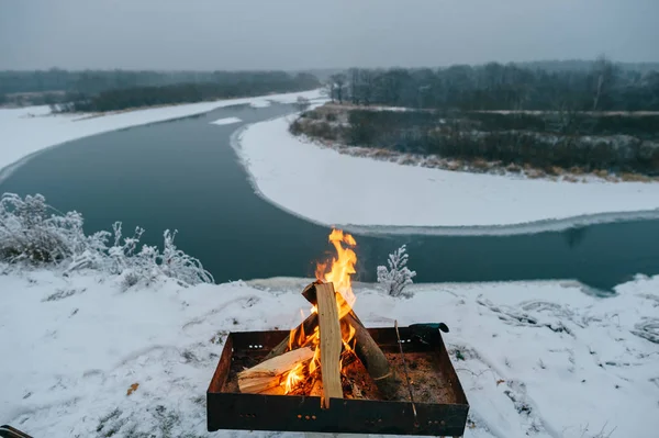 fire of wooden logs in brazier in snow