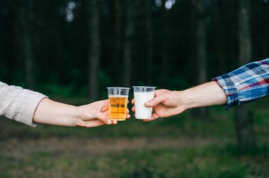 insanların kısmi görünümü ormanda süt ve bira ile plastik gözlük clinking