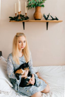 genç kadın yatakta otururken küçük kedi yavrusu sarılma