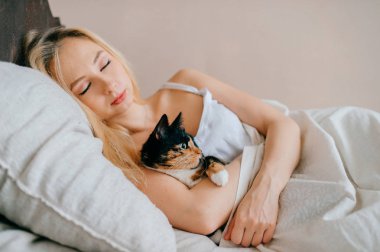 kadın yatakta uyurken küçük kedi yavrusu sarılma