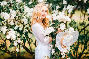 Bahar çiçek açan bahçede poz beyaz elbiseli genç güzel kadın