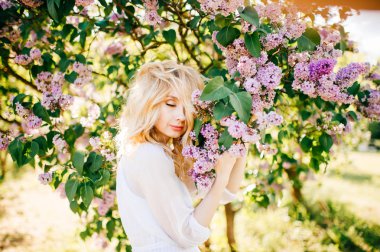 Çiçek bahçesinde beyaz elbiseli genç güzel sarışın kadın