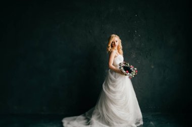 karanlık duvar arka plan üzerinde poz beyaz şık gelinlik güzel zarif gelin