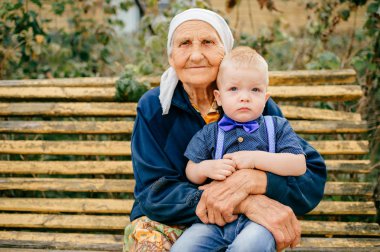Büyükanne torunu ile bahçede bankta oturmuş