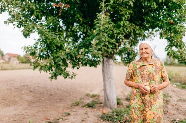 Yaz bahçede duran elinde apple ile yaşlı kadın
