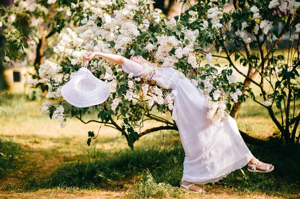 春咲く庭でポーズをとって白いドレスの若い美しい女性 — ストック写真