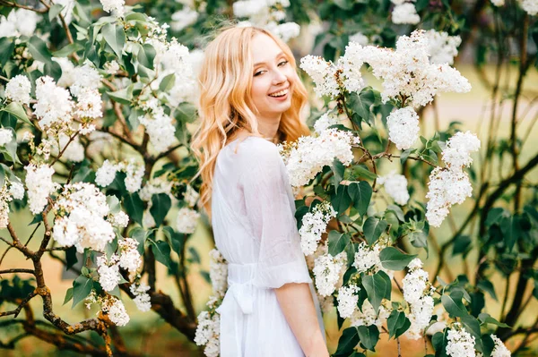 春咲く庭でポーズをとって白いドレスの若い美しい女性 — ストック写真
