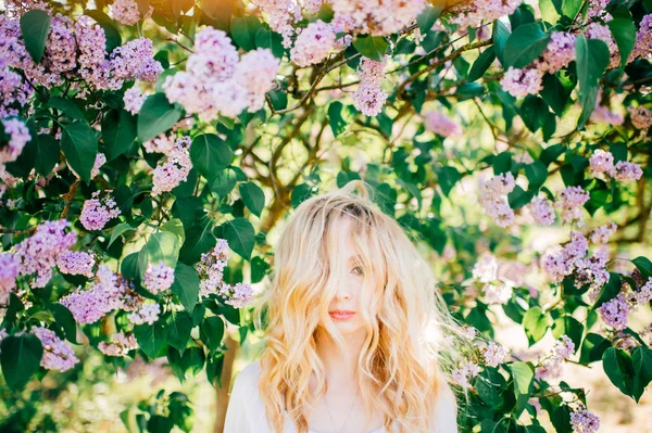 白いドレスの咲く庭でポーズの若い美しい女性 — ストック写真