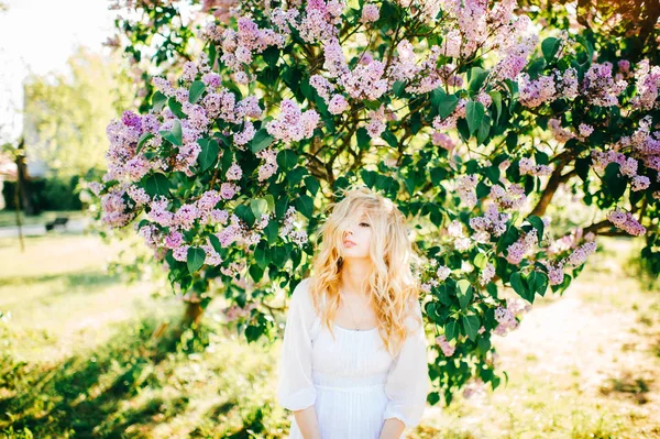 白いドレスの咲く庭でポーズの若い美しい女性 — ストック写真