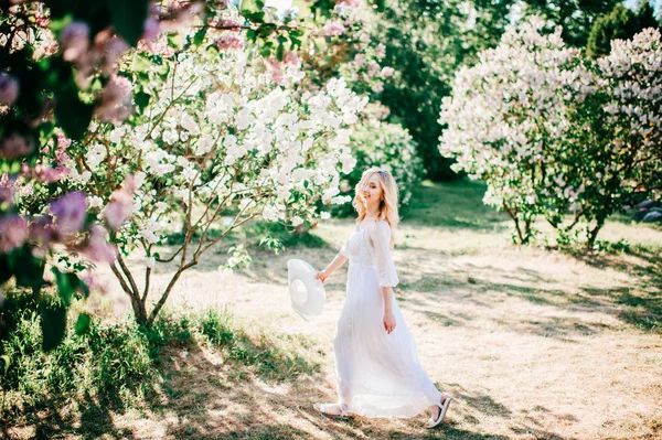 ブルーミング ガーデンの白いドレスで若いかなりブロンドの女性 — ストック写真