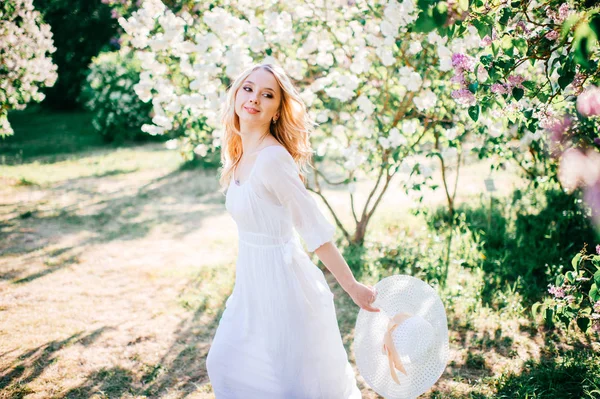 年轻漂亮的金发碧眼的女人在盛开的花园白色礼服 — 图库照片