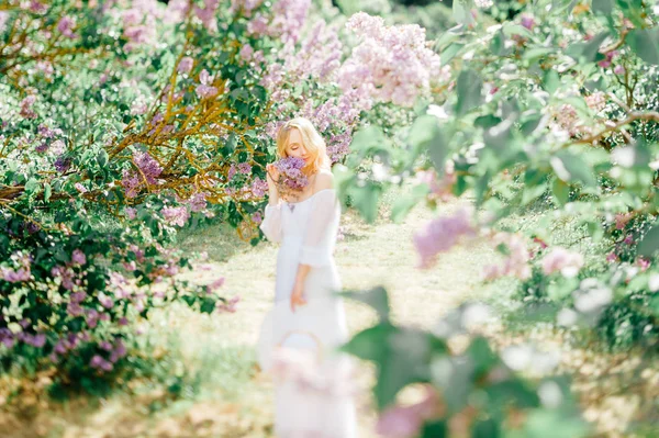ブルーミング ガーデンの白いドレスで若いかなりブロンドの女性 — ストック写真