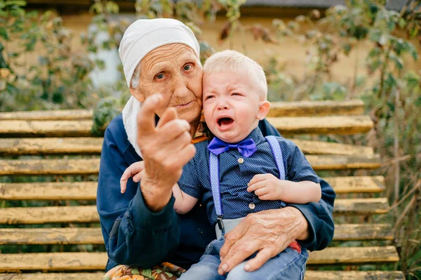 grandmother sitting with crying grandson on bench in yard