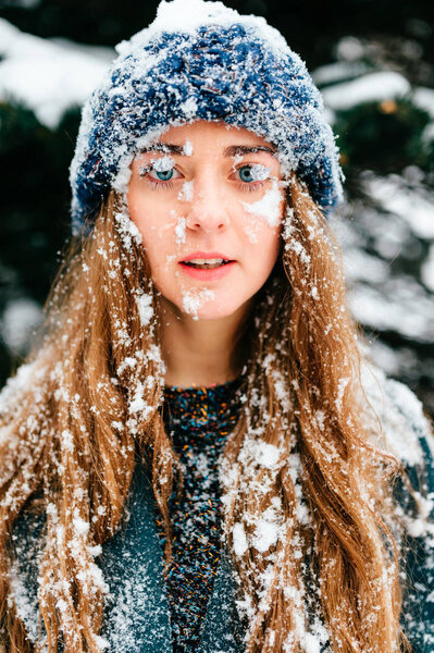Young beautiful woman posing in snowy forest on winter day
