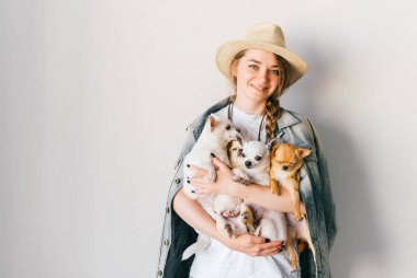 Hasır şapka ve denim ceket chihuahua kukla tutan genç kadın