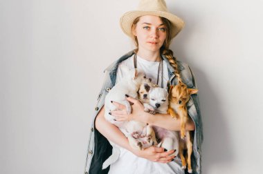 Hasır şapka ve denim ceket chihuahua kukla tutan genç kadın