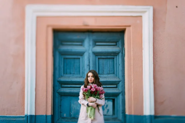 美丽的年轻女子与郁金香花束摆在街上 — 图库照片