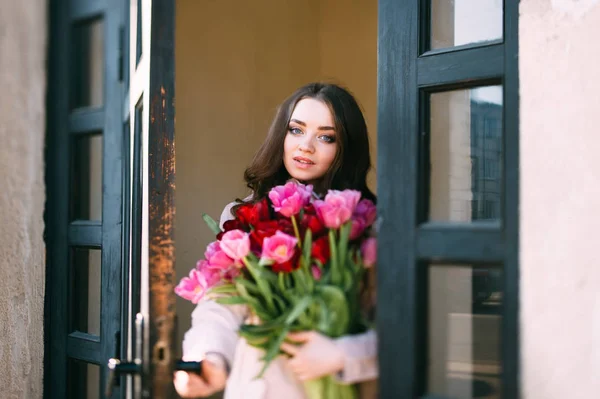 美丽的年轻女子与郁金香花束摆在街上 — 图库照片