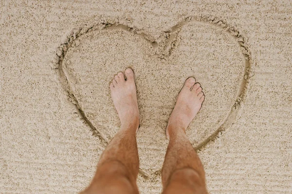 partial view of barefoot man on sandy beach