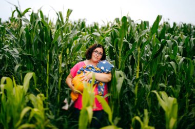 Mısır tarlasında ayakta eller üzerinde bebek kadınla