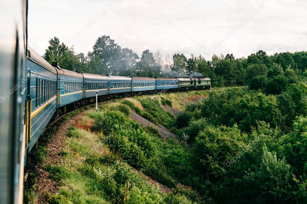 Vintage locomotive with old wagons riding along countryside 