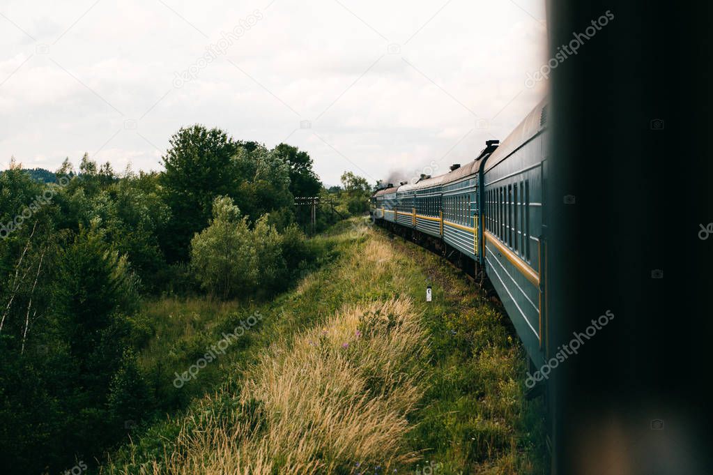 Vintage locomotive with old wagons riding along countryside 