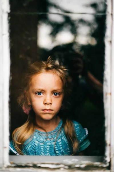 Dziewczynka Niebieską Sukienkę Dzianiny Patrząc Przez Okno — Zdjęcie stockowe