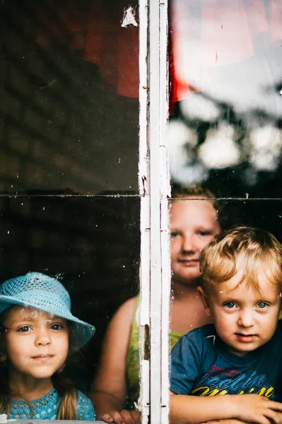 Små Flickor Och Pojke Som Står Nära Fönstret Hemma — Stockfoto