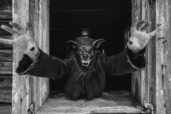 black and white photo of person in creepy mask in wooden house