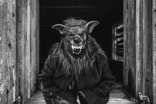 black and white photo of person in creepy mask in wooden house