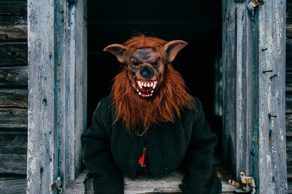 obscured view of person in creepy mask in wooden house