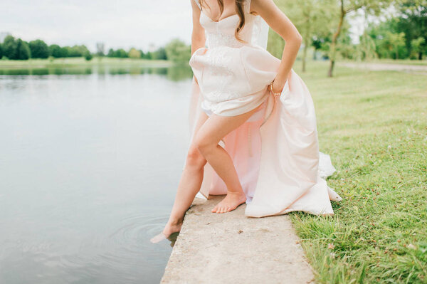 Partial view of bride in stylish wedding dress standing at river
