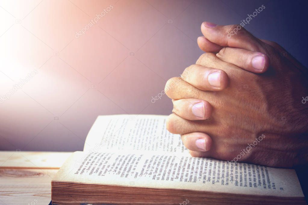 praying hands over a holy bible
