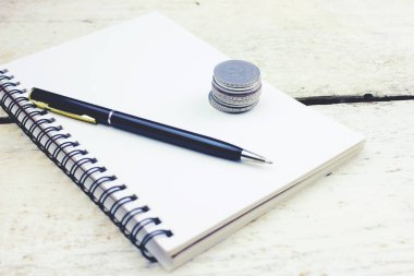 Defter ve kalem ile ahşap bir masa üzerinde paralar