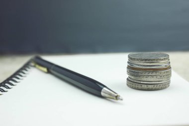 Defter ve kalem ile ahşap bir masa üzerinde paralar