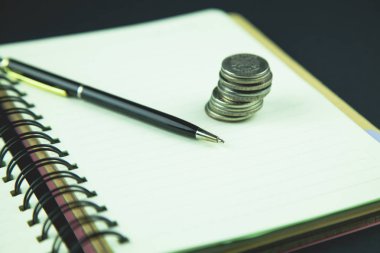 Defter ve kalem ile ahşap bir masa üzerinde paralar