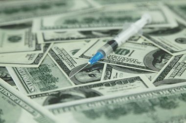 Şırınga ve para masada.