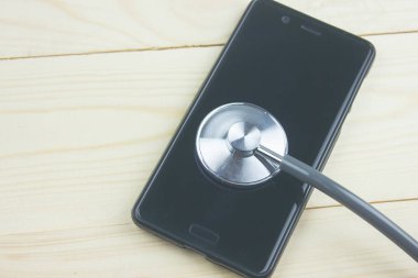 bir stetoskop ve ahşap bir masa üzerinde bir telefon