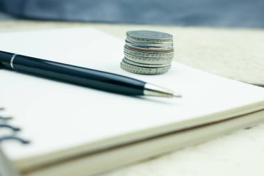Defter ve kalem ile ahşap bir masa üzerinde paralar