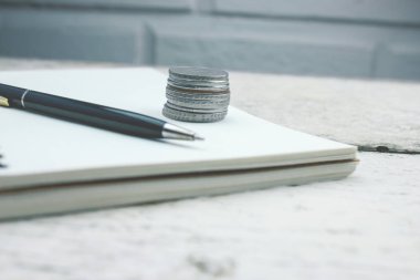 Defter ve kalem ile ahşap bir masa üzerinde paralar