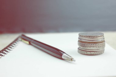 Defter ve kalem ile ahşap bir masa üzerinde paralar