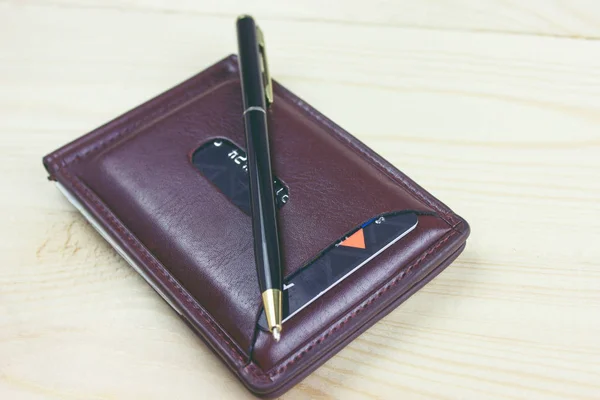 Pen and wallet on wooden table Stock Photo