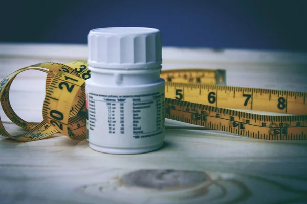 Centímetro e pílulas em uma mesa de madeira — Fotografia de Stock