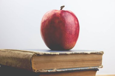 Kırmızı elma ve masanın üzerine kitaplar