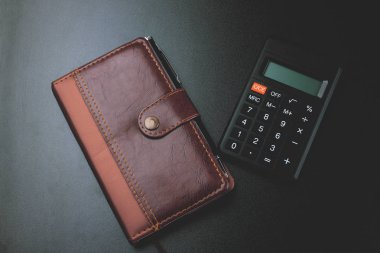 Masanın üzerinde bir not defteri ile hesap makinesi