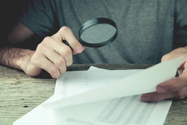 Hombre manos buscando documento con lupa — Foto de Stock