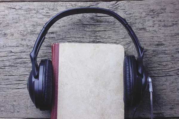 Навушники і книга на дерев'яному столі — стокове фото