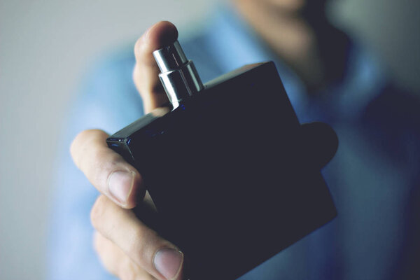 Мужчина посыпает себя духами
